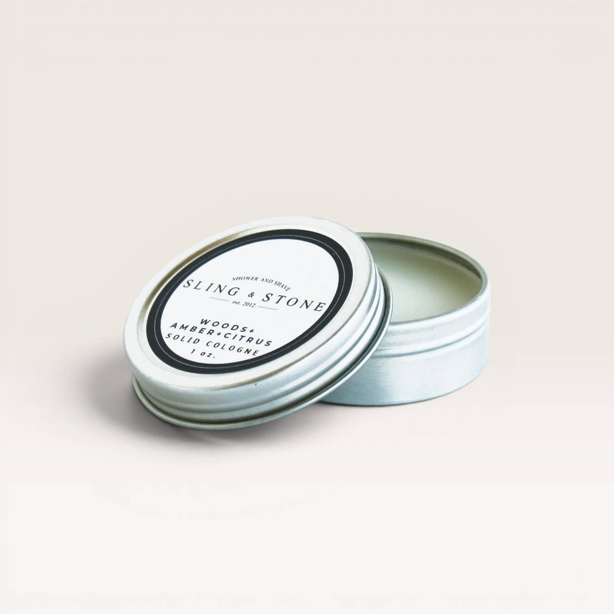 Sling & Stone solid cologne tin on a light beige background
