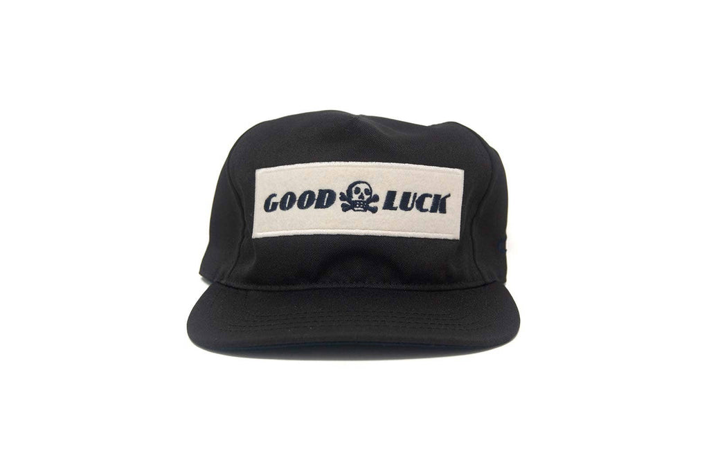 Black cap with 'Good Luck' patch on a white background