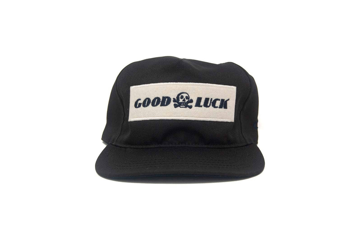 Black cap with 'Good Luck' patch on a white background