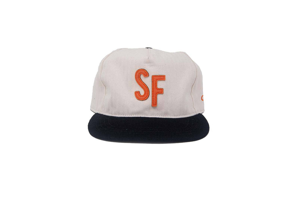 A structured baseball cap with an off-white crown, a dark navy flat brim, and a prominent orange embroidered 'SF' logo on the front, set against a plain white background.