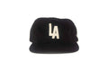 Black cap with 'LA' logo on a white background