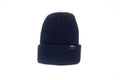 A dark navy blue ribbed knit beanie hat with a folded cuff, featuring a small black brand tag on the side, set against a plain white background.