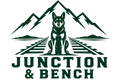 A dark green and white graphic logo featuring a seated dog centered on railroad tracks, with jagged mountains above and the text 'JUNCTION & BENCH' below.
