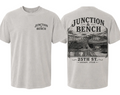 Front and back views of a light gray crewneck t-shirt. The front features a small black graphic on the left chest reading 'JUNCTION BENCH'. The back features a photo of 25th St. Ogden, Utah.