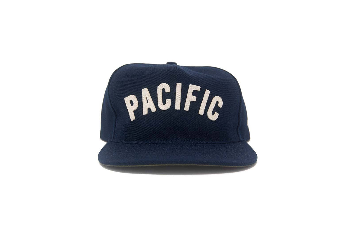 Navy blue cap with 'PACIFIC' text on a white background