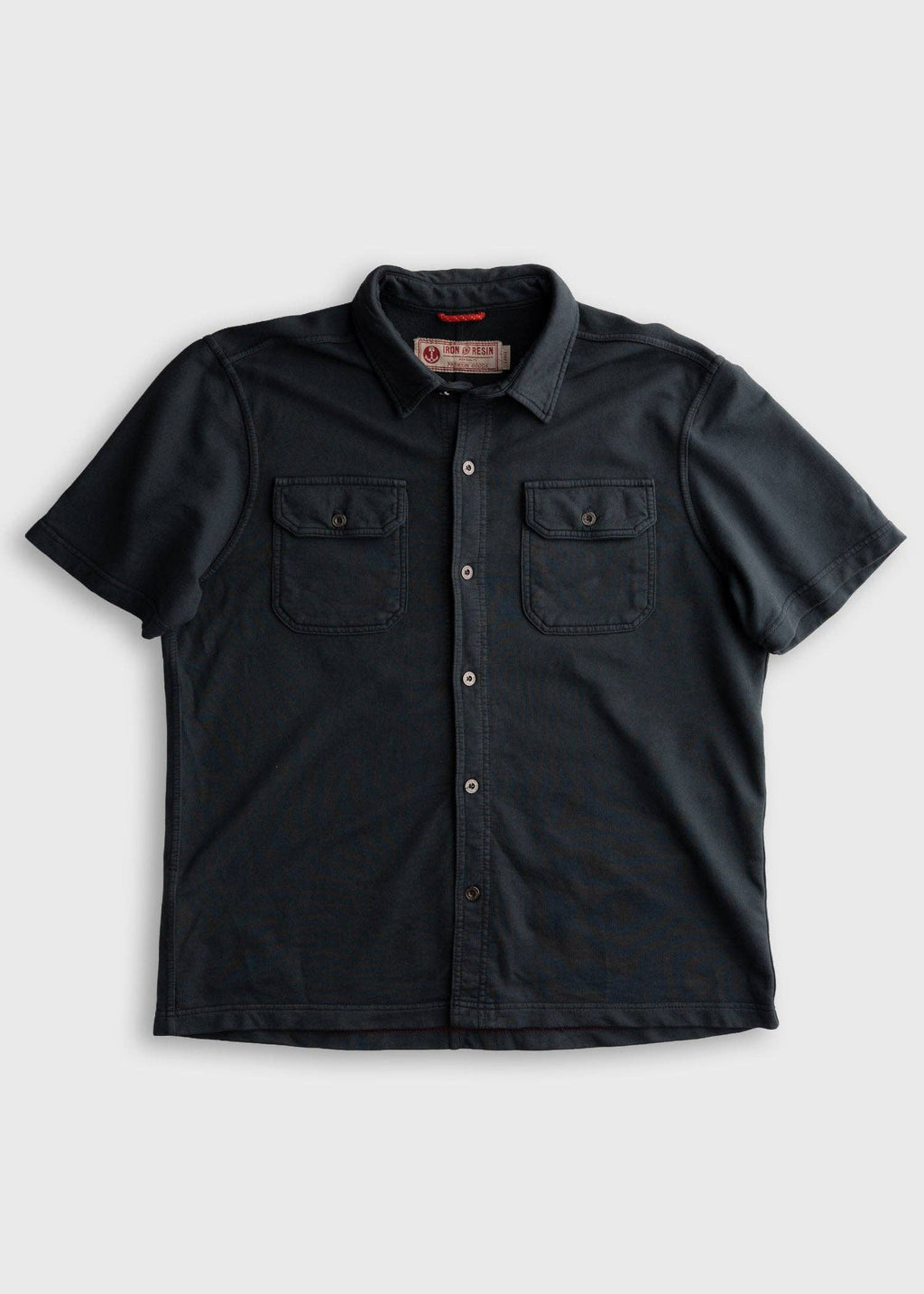 Black short-sleeve shirt with button details on a light gray background