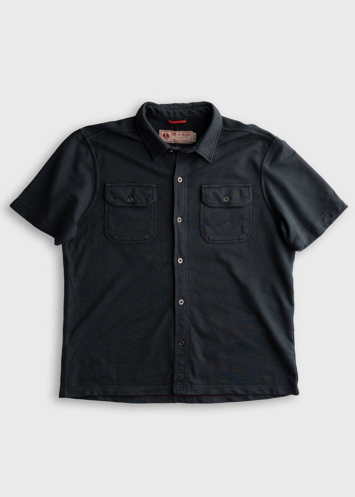 Black short-sleeve shirt with button details on a light gray background
